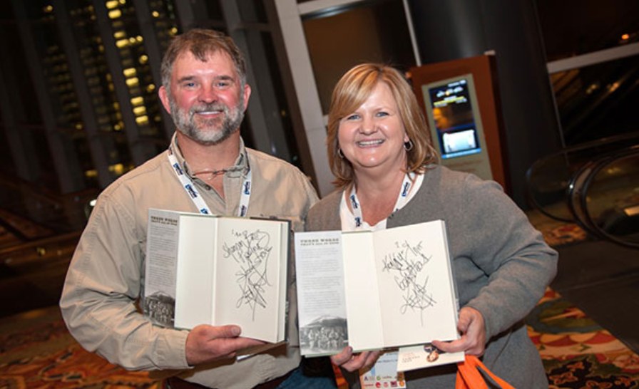 Two attendees smiling with their signed copies of Keni's book