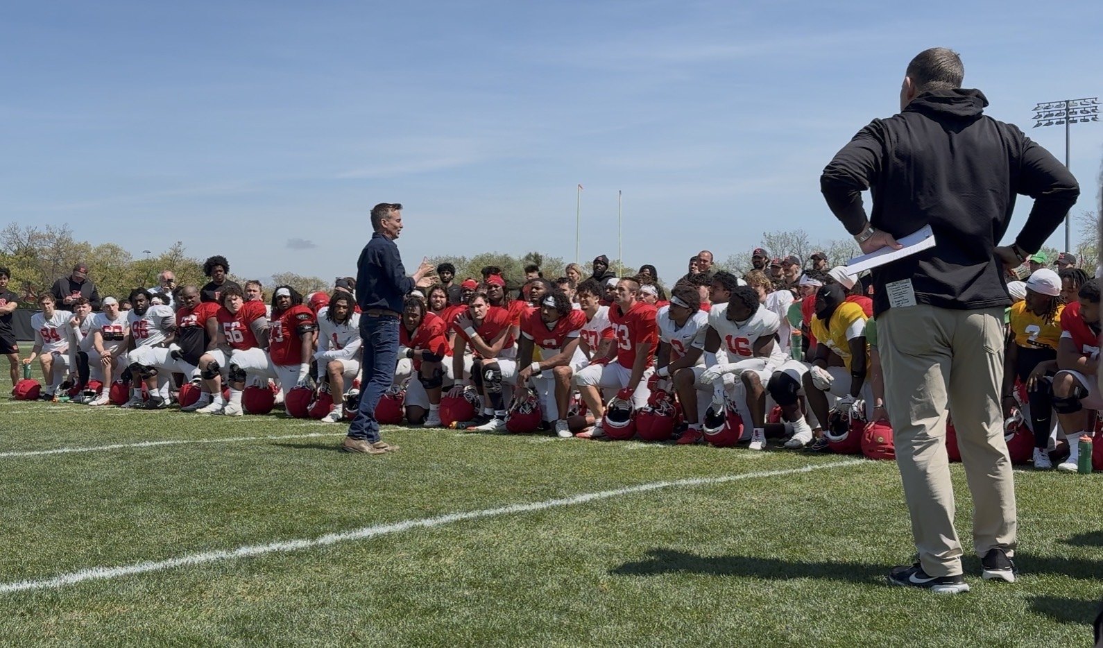Keni Thomas speaking to a college football team on the practice field